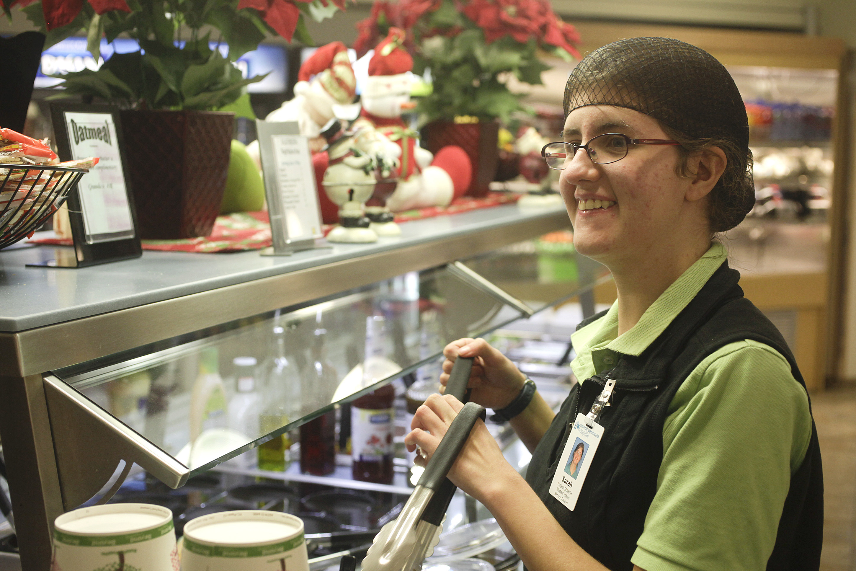 Sarah Mohorcich laughs and sings along with Christmas music as she stocks a salad bar in the cafeteria at Central Peninsula Hospital last week. Mohorcich is an intern with Project SEARCH which provides job training for students with disabilities. -Photo by Rashah McChesney, Morris News Service - Alaska