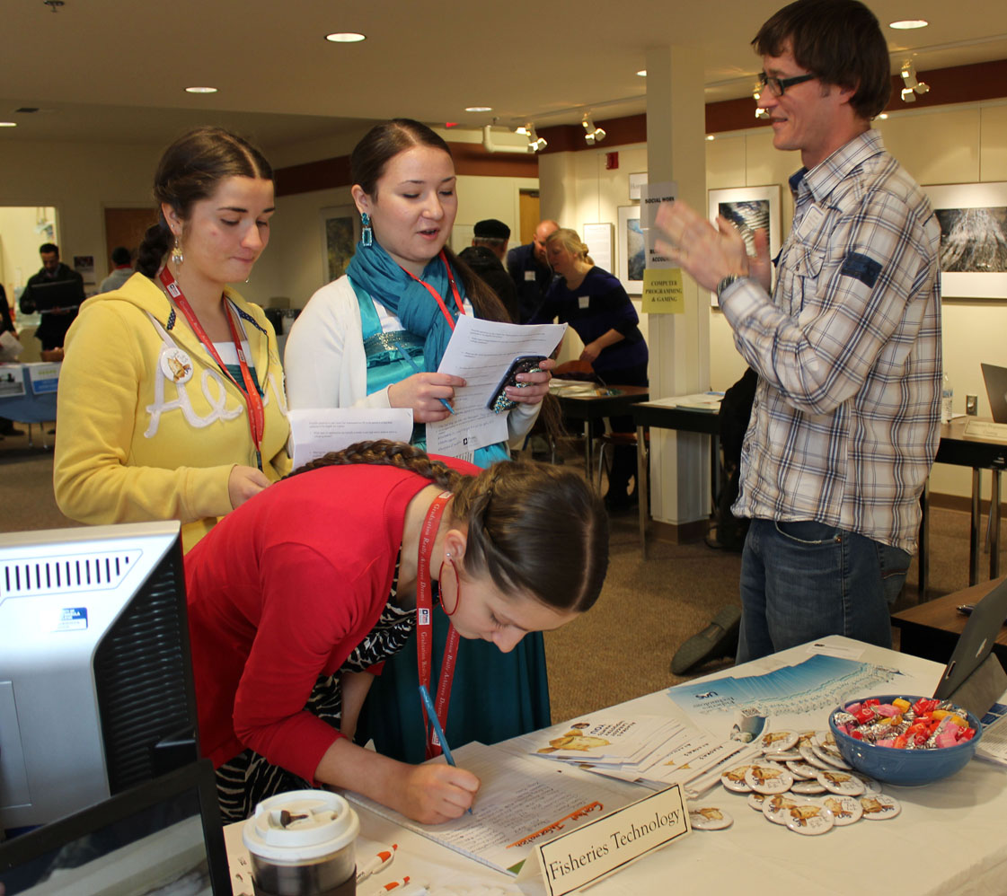 Project GRAD students from Kachemak Selo — from left, Ksenia Reutov, Mariania Reutov and Katherine Konev — ask Joel Markis of the University of Alaska Southeast questions about the university’s fisheries technology program during last week’s College, Career and Job Fair at the Kachemak Bay Campus. The fair was a chance for students and the public at large to meet with employers, explore options for a variety of jobs and careers, and learn  more about what the University of Alaska offers in Homer as well as other UA campuses.-Photo by McKibben Jackinsky, Homer News