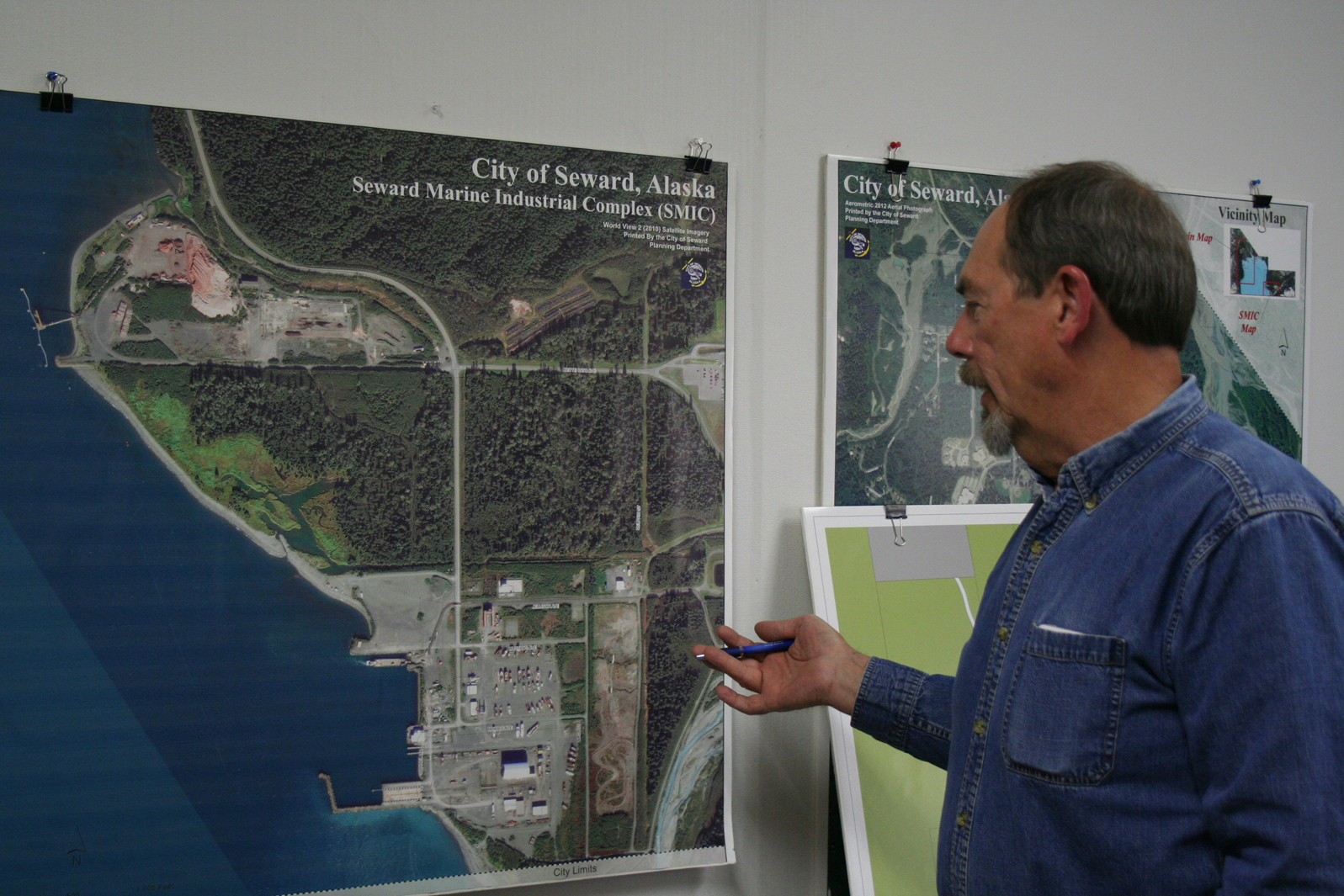 Seward Community Development Director Ron Long discusses the city’s plans for the Seward Marine Industrial Center across Resurrection Bay from its population center in front of a photo of the shipyard and surrounding area.