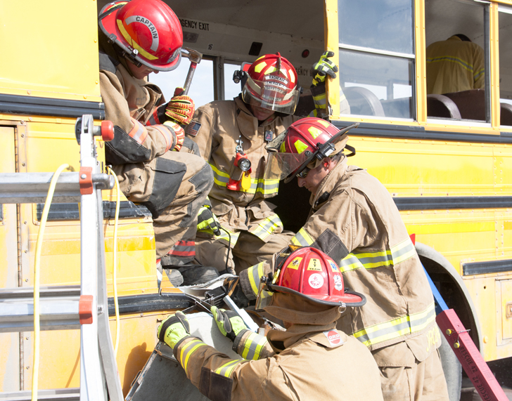 Firefighters from Homer and the Alpine Fire Department work together to open the side of a school bus.-Photo by Heather Ericson