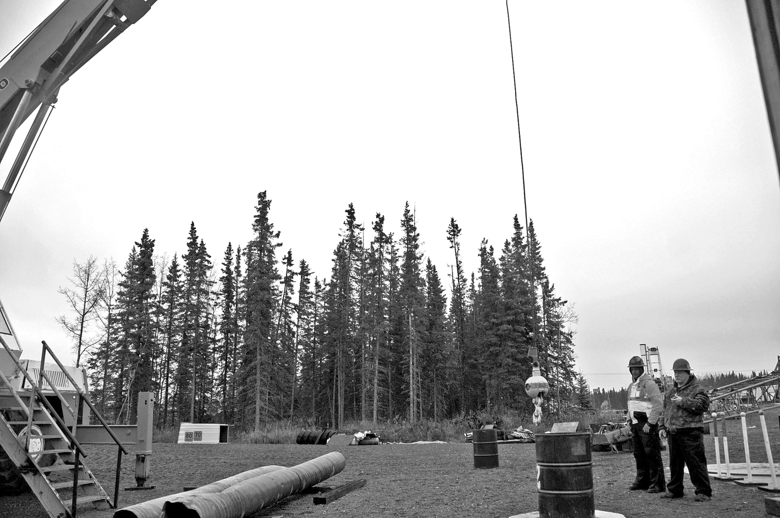 Bill Elmore and Daniel Barry watch and time Brandon Leary as he attempts to lower the auxiliary ball of a crane into a barrel, one of the certification practical exam requirements.-Photo by Elizabeth Earl, Morris News Service - Alaska