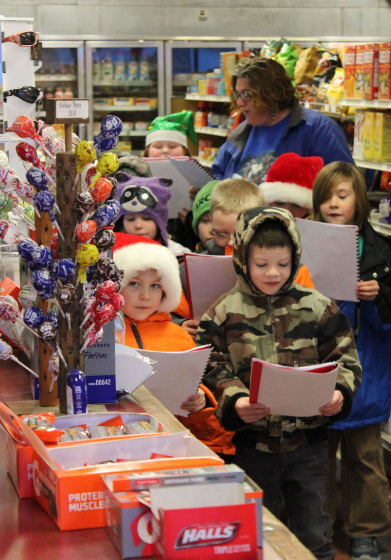 students in Lila Johnson’s second-grade class at Chapman School carol at Anchor River Inn Store-Photos by Michael Armstrong and McKibben Jackinsky, Homer News; and Derotha Ferraro