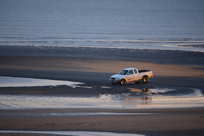 A person drives a truck through tidepools at Bishop’s Beach.-Photo by Michael Armstrong, Homer News