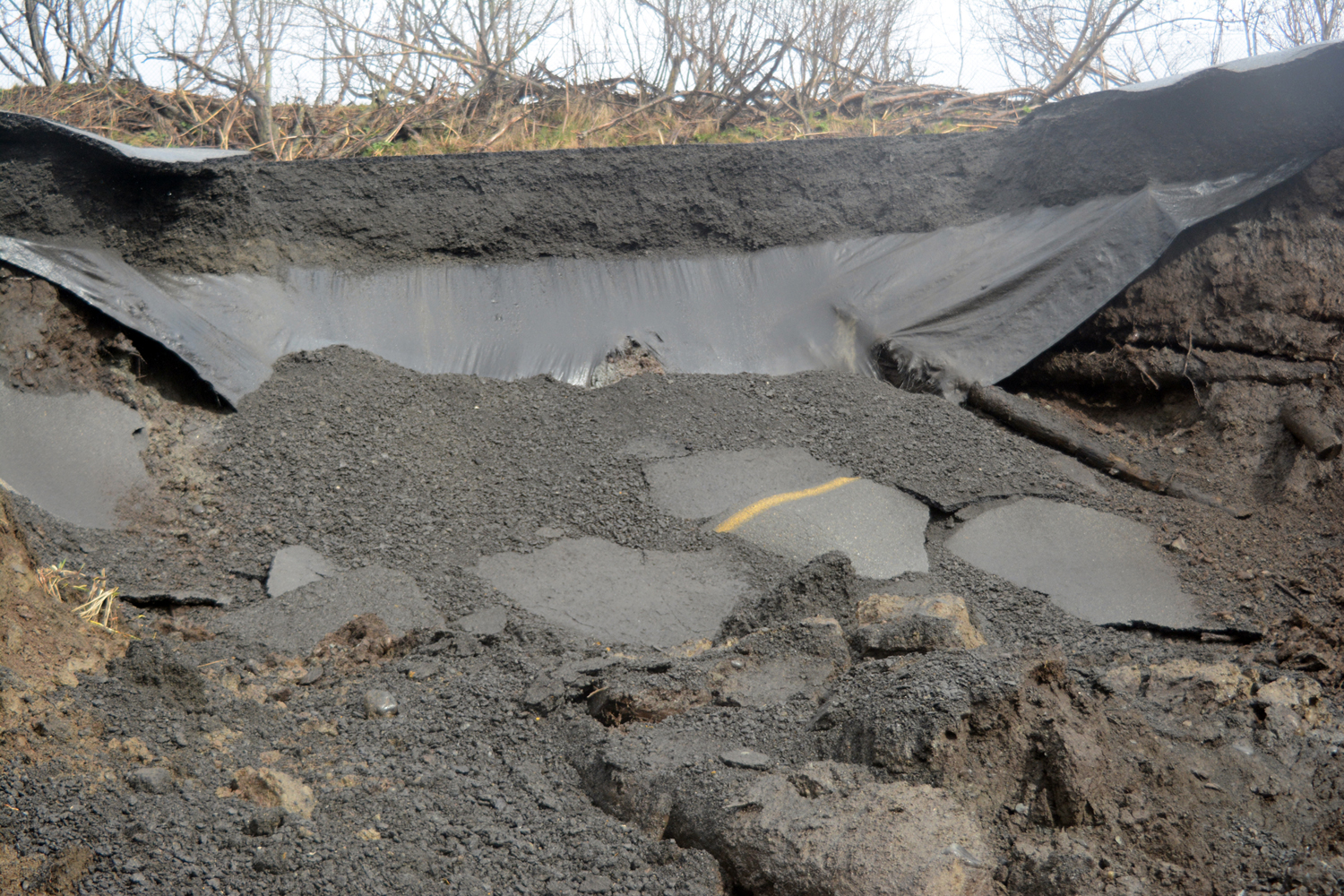 Filter fabric hanges below a section of Kachemak Drive that washed out on Sunday,-Photo by Michael Armstrong, Homer News