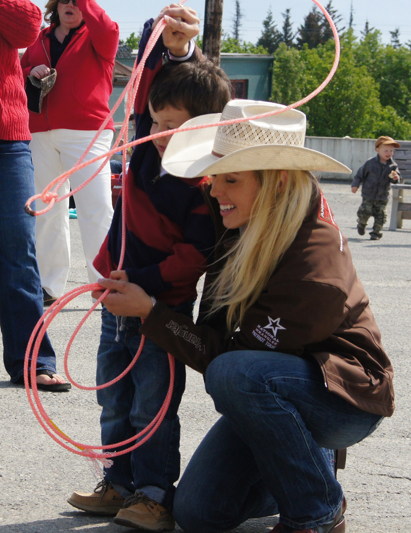 Megan Ridley, Miss Wrangler National Patriot/2009 Miss Rodeo America, helps a youngster learn some roping tricks during a visit by the Wrangler National Patriot Memorial Day Tour on Sunday. -Photo provided