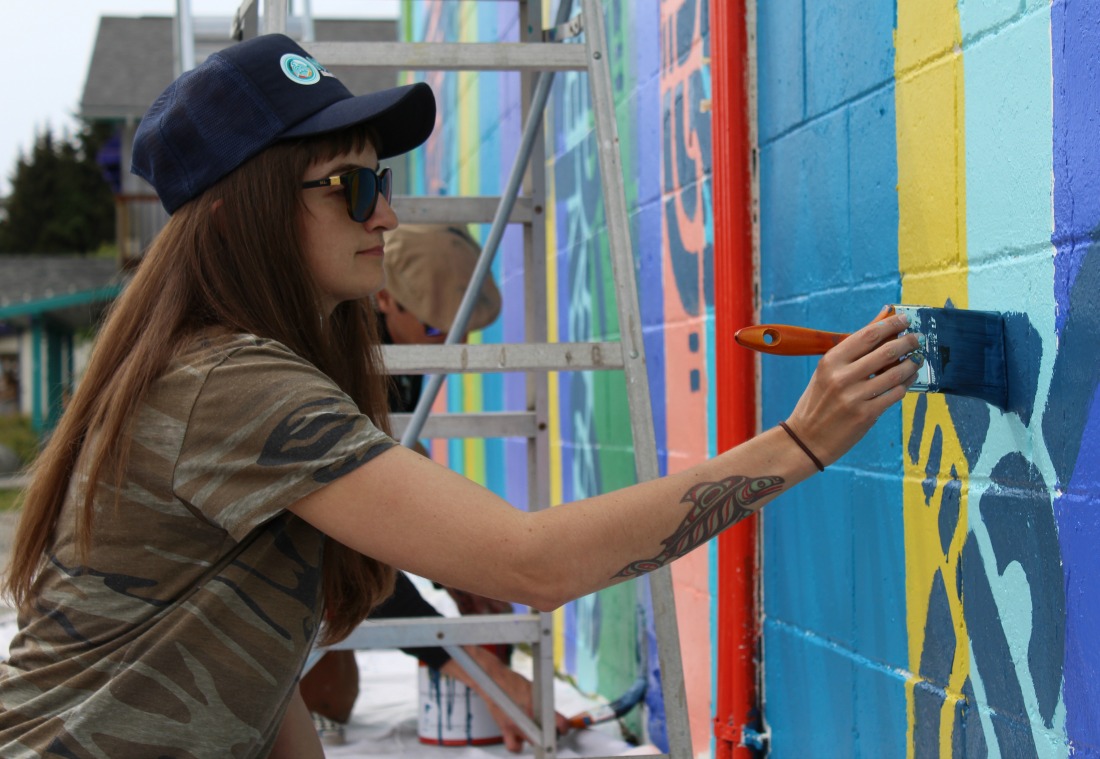 Spellar mural group painter Bailey Gamble paints part of a pattern on the Star Car Wash mural, the first mural of Bunnell Street Art Center’s Peonies on Pioneer public art campaign.-Photo by Anna Frost, Homer News