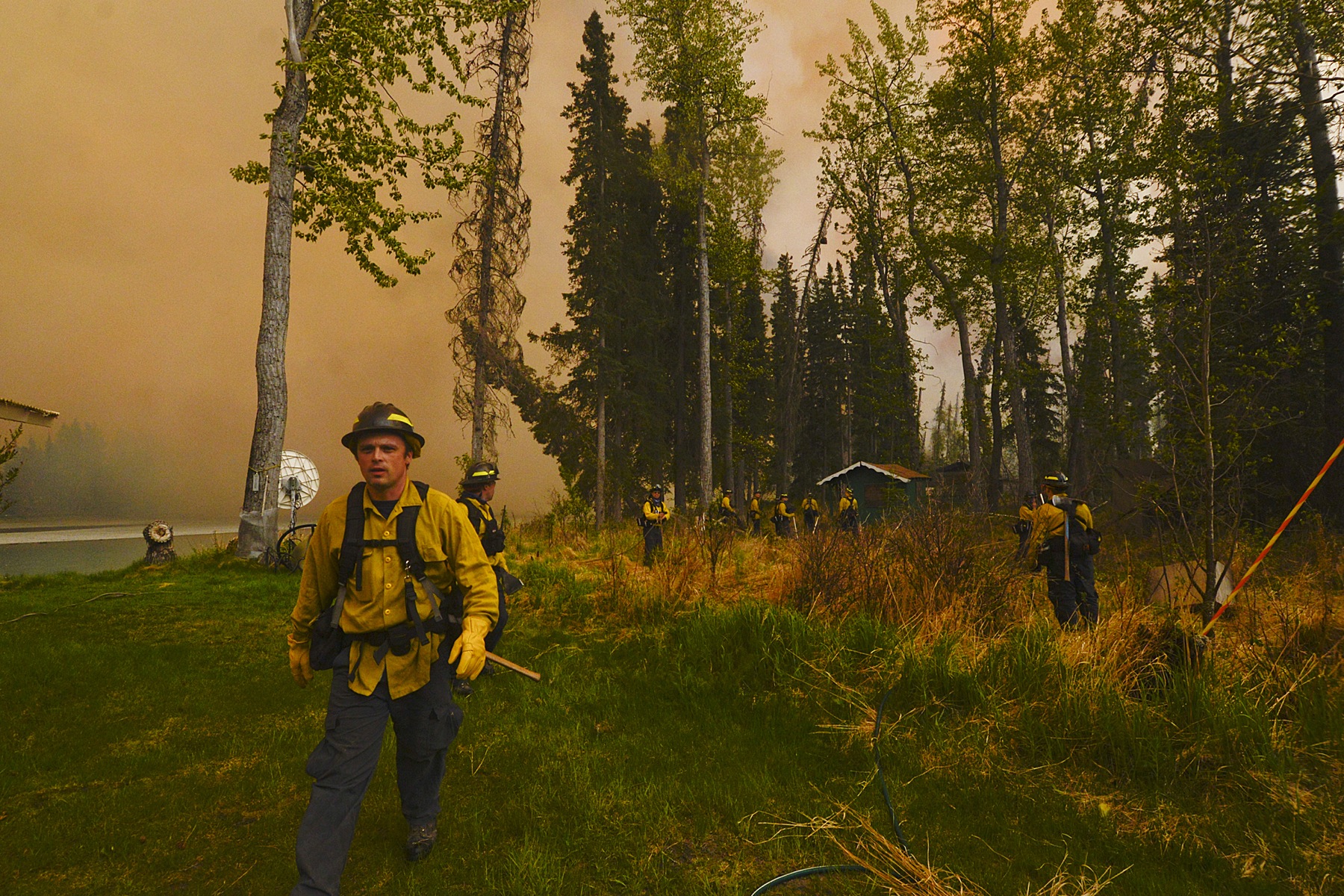 Central Emergency Services firefighters, dwarfed by 150 foot flames and thousands of feet of smoke, assess whether they can protect a property near the intersection Fisherman's Road and Killey Street Sunday May 25, 2014 in the Funny River community of Soldotna, Alaska. A 156,041 acre wildfire has been threatening the community — which was largely evacuated late Sunday — for four days.-Photo by Rashah McChesney/Morris News Service-Peninsula Clarion