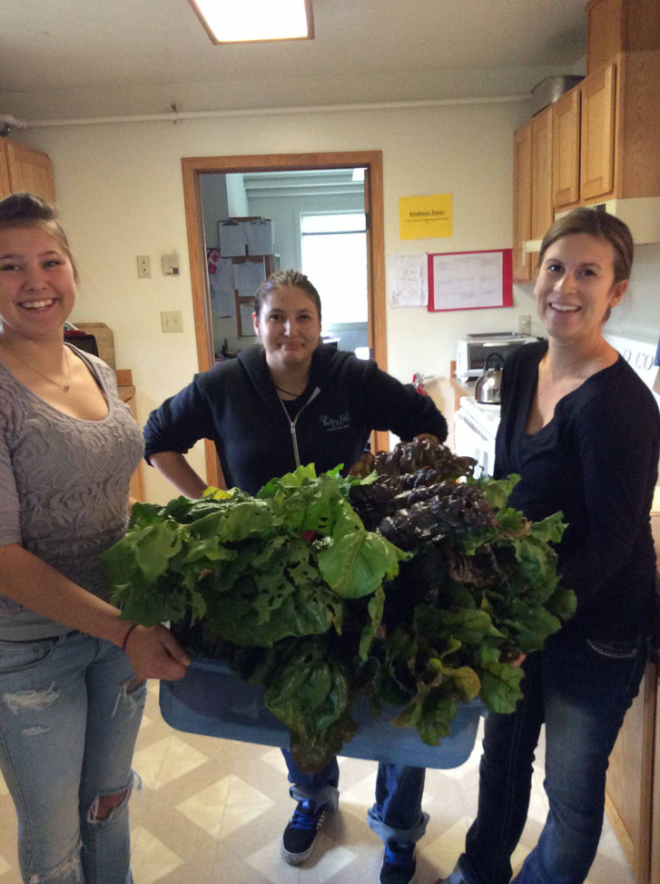 Homer Flex students Crystal Campbell, left, and Alexia Wrenn, and skills trainer Jackie Kondak harvest fresh vegetables from the school’s garden. Vegetables from the garden were prepared in a number of ways and served at the school’s recent open house.