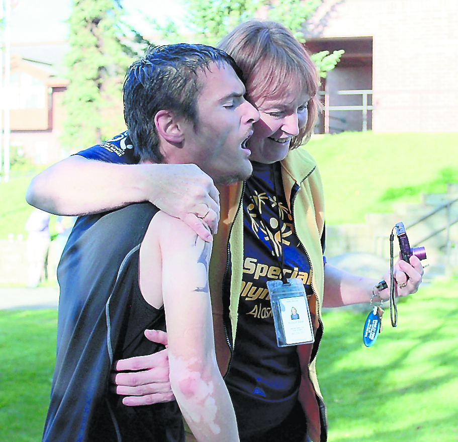 After completing a 5-mile run, the last leg of Saturday’s 14th annual Homer Ironman Triathlon, Scott Trail, runner on the Special Olympics unified team, gets a hug from team coach Ruhiyyiah Baker.