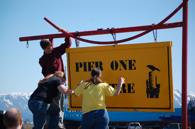 Emmet Meyer, left, and Laura Norton, center, and Esther Lowe, right, put up the Pier One Theatre sign on the Homer Spit on Saturday.-Michael Armstrong, Homer News