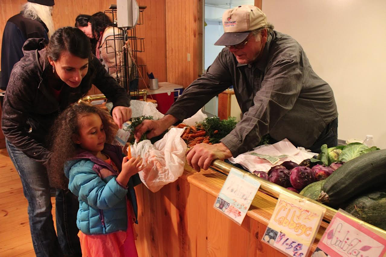 In photo at right, Megan Palma and 4-year-old Aria Palma purchase carrots from local farmer Robert Durr on opening day of Alaska Wild Berry Emporium.