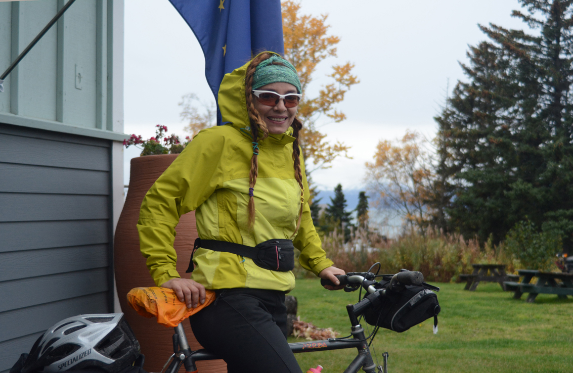 Marite Perez poses in front of the Alaska flag at the Homer Chamber of Commerce and Visitor Center last Friday. Perez, 44, of Merida, Venezuela, biked into Homer last week after biking 1,600 miles from San Francisco, Calif. Perez did part of her trip on the Alaska ferry from Bellingham, Wash., to Haines. She started on June 21.  “Alaska is incredible. It is magnetic, totally,” Perez said, “On this trip I’ve been meeting the most incredible people.” In Venezuela, Perez works as a hiking guide, taking people on treks into the rain forests.-Photo by Michael Armstrong, Homer News
