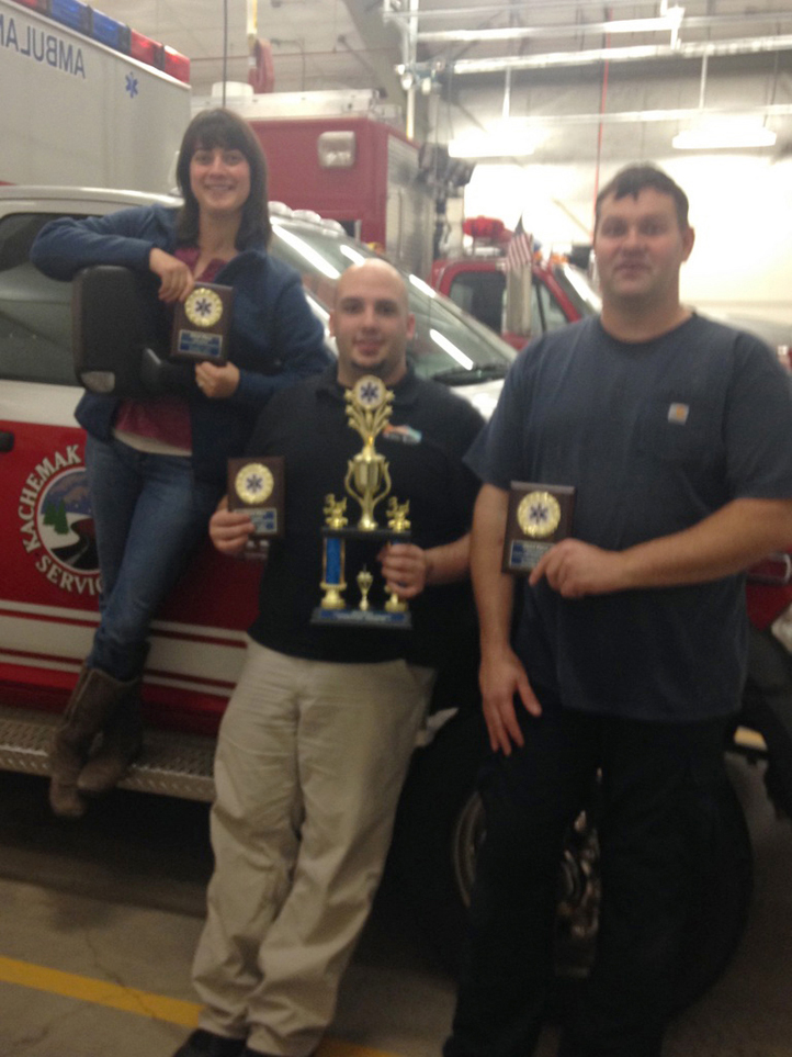 Kachemak Emergency Services volunteers, from left, Kerbey Lyon, Emergency Medical Technician I,  Phillip Boyle, EMT III,  and Joe Sallee, EMT III, pose with their awards by a KES ambulance.