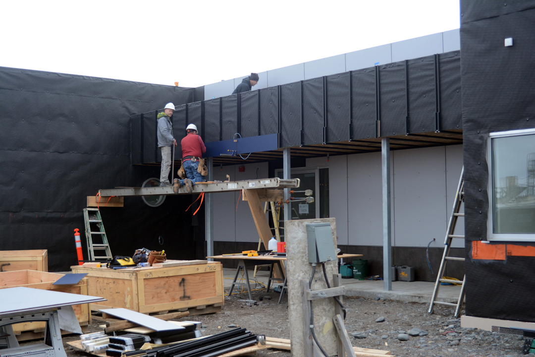 Workers last Thursday install siding at the entrance to the new Harbormaster’s Office.-Photo by Michael Armstrong, Homer News
