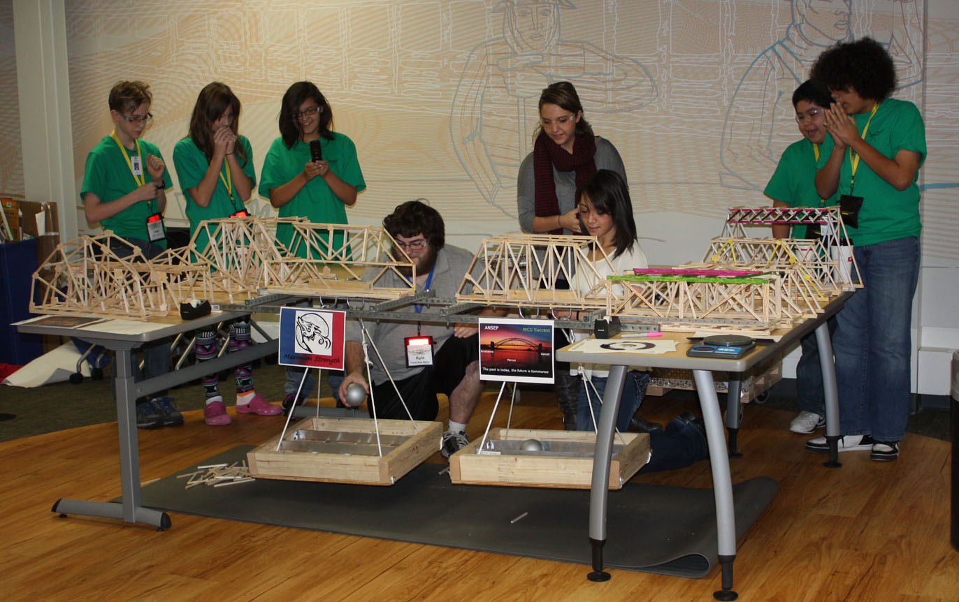 Daylynn Yenney of Homer, third from left; Garrett Cooper of Anchor Point, far right; and other participants of the Alaska Native Science and Engineering Program Middle School Academy observe the strength of a bridge built during the academy.