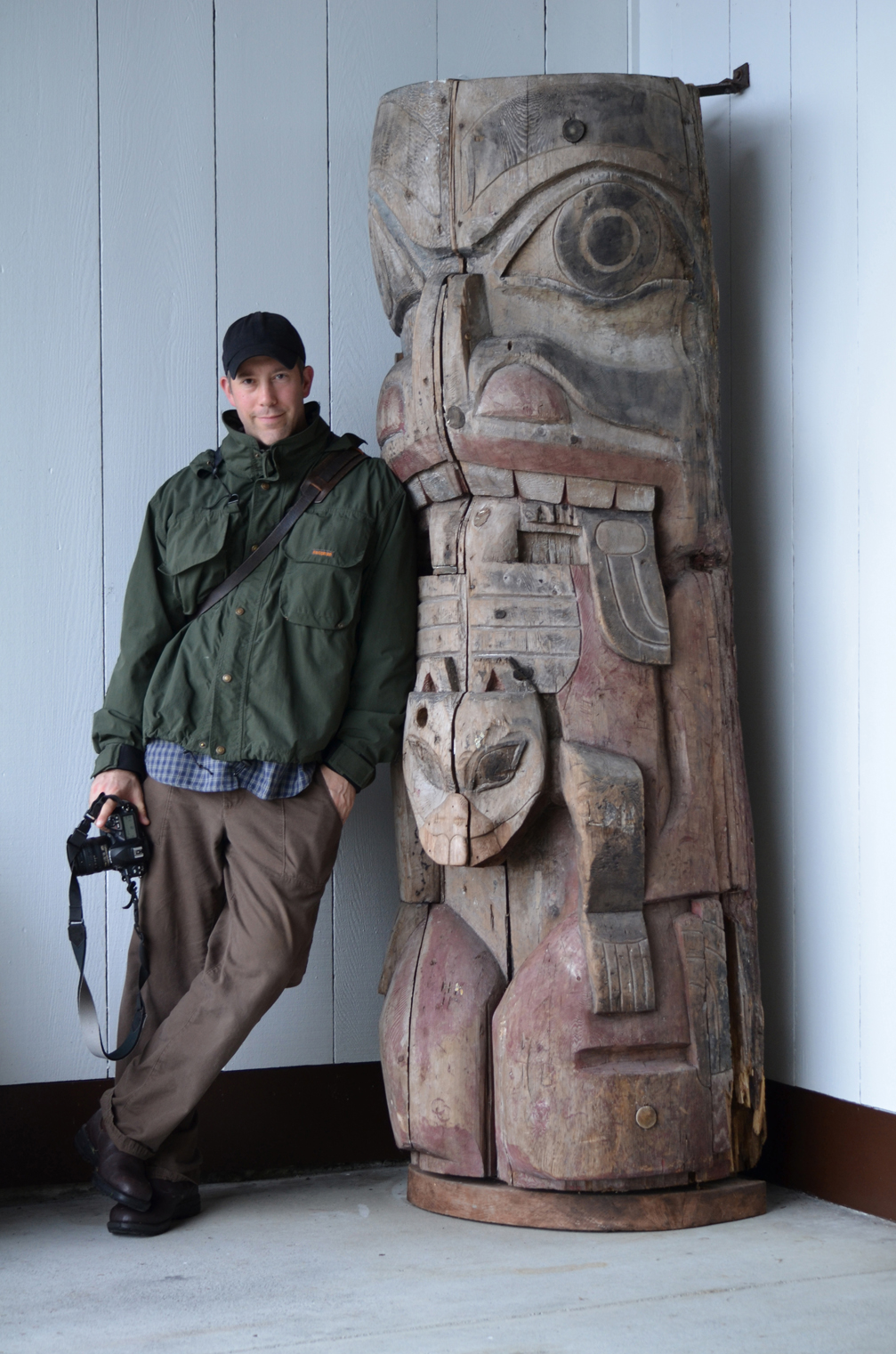 Chris Bernard stands beside a Haida totem pole at Sitka National Historical Park on visit to Alaska while researching his book. -Photo by Kim  Bernard