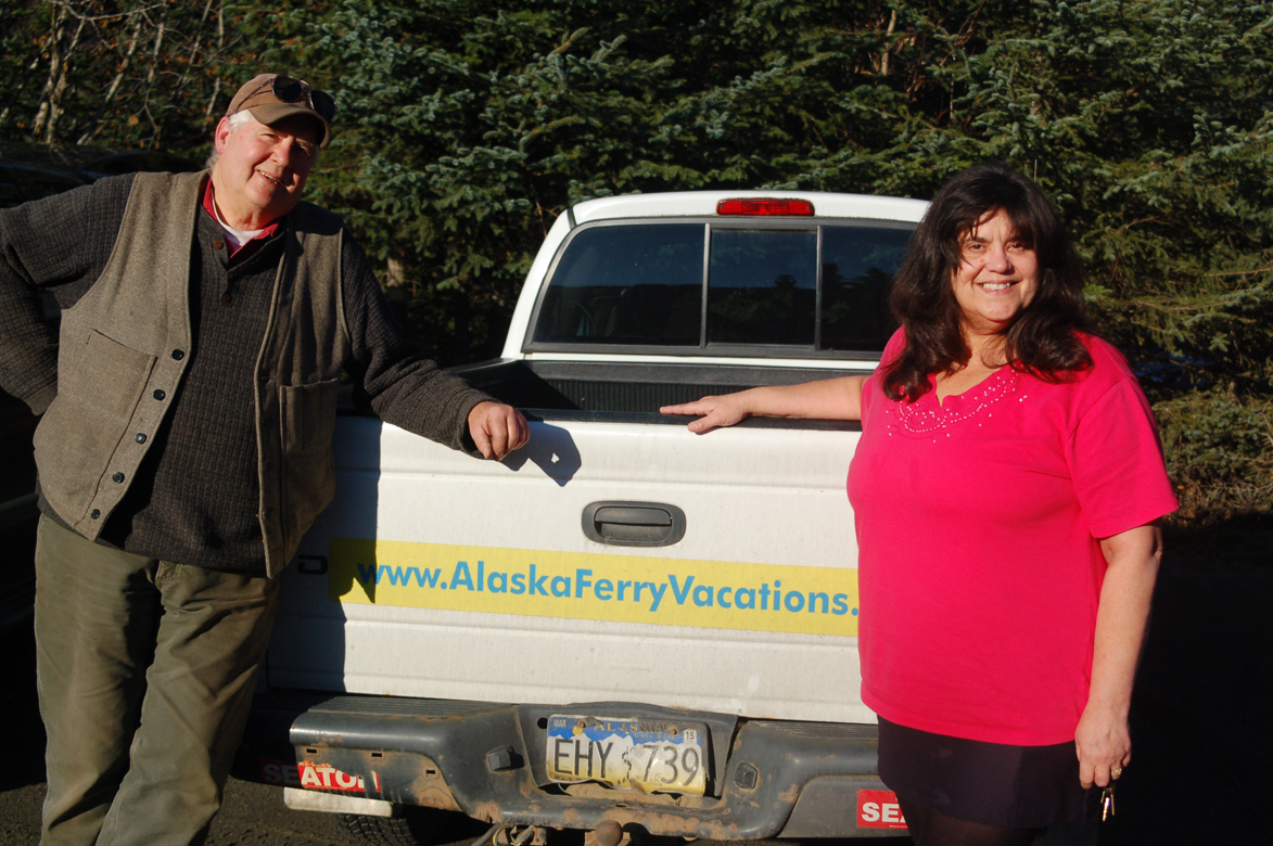 Phil Morris, left, and Pat Merrill, right, of Alaska Ferry Adventures & Tours stand by Morris’ truck advertising the tour company’s website.-Photo by Michael Armstrong, Homer News