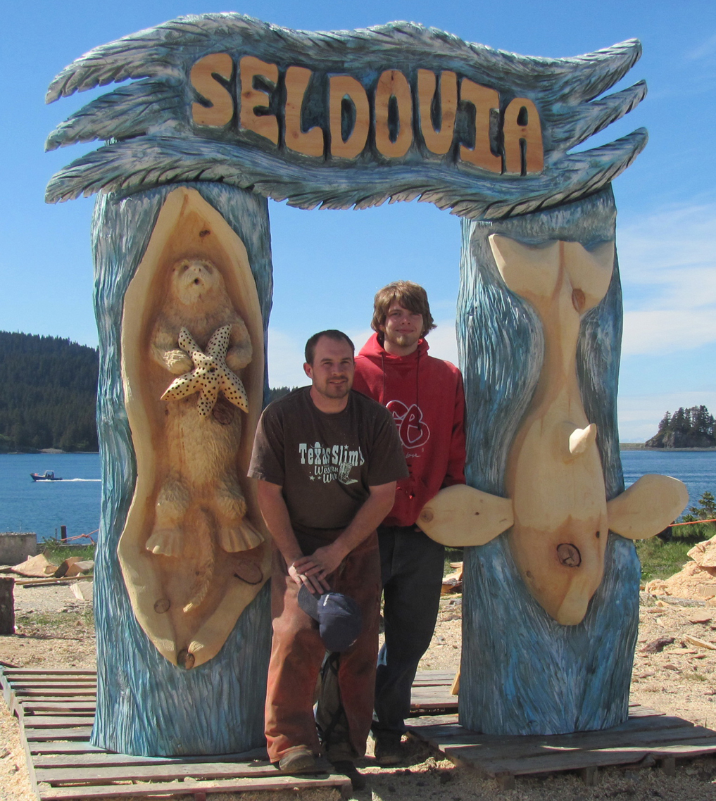A carving team stands by the new Seldovia sign they created using chainsaws.   -Photo by Jenny Chissus