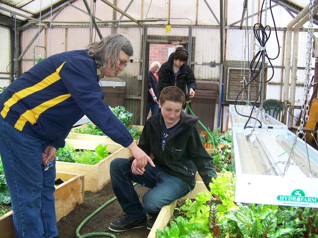 Homer High School teacher Francie Roberts, left, looks at gardens being grown by Johann Kallelid, foreground, Robert Dinneen, background, and other students in school’s natural resources class.-Photo by McKibben Jackinsky, Homer News