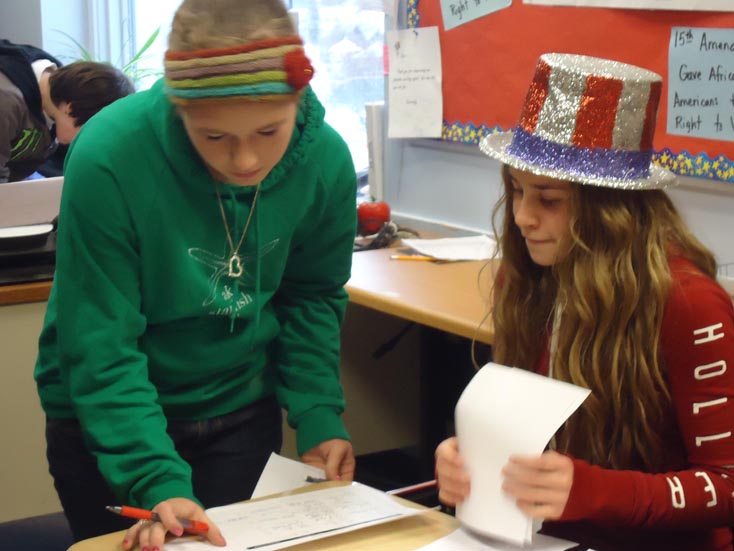 Homer Middle School eighth-grade students Annali Metz, left, and Lauren Evarts of Suzanne Haines’ U.S. History class help with the school’s “Electing a President” simulation.-Photo provided