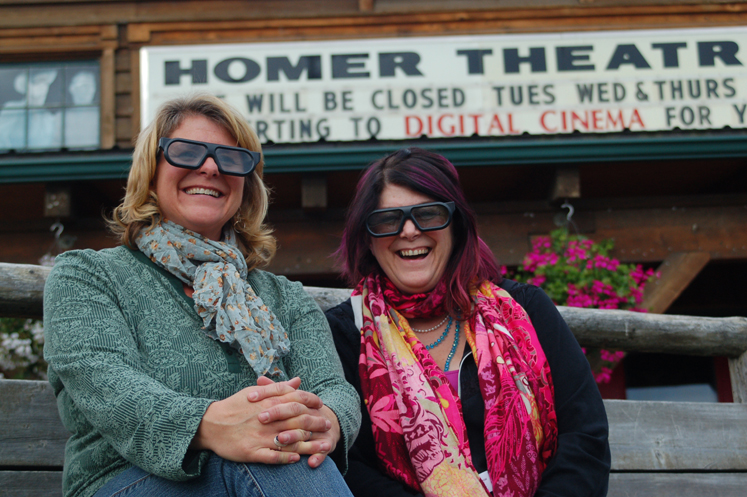 Homer Theatre programming manager Colleen Carroll, left, and Robin Daugherty, right, former operations manager, model the glasses used to view 3-D films when the theater went digital in September 2011.-Photo by Michael Armstrong, Homer News