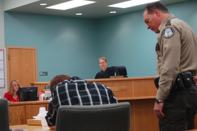 Zachary Fraley, 18, signs release papers as a jail officer and Magistrate Jennifer Wells watch.-Photo by Michael Armstrong, Homer News