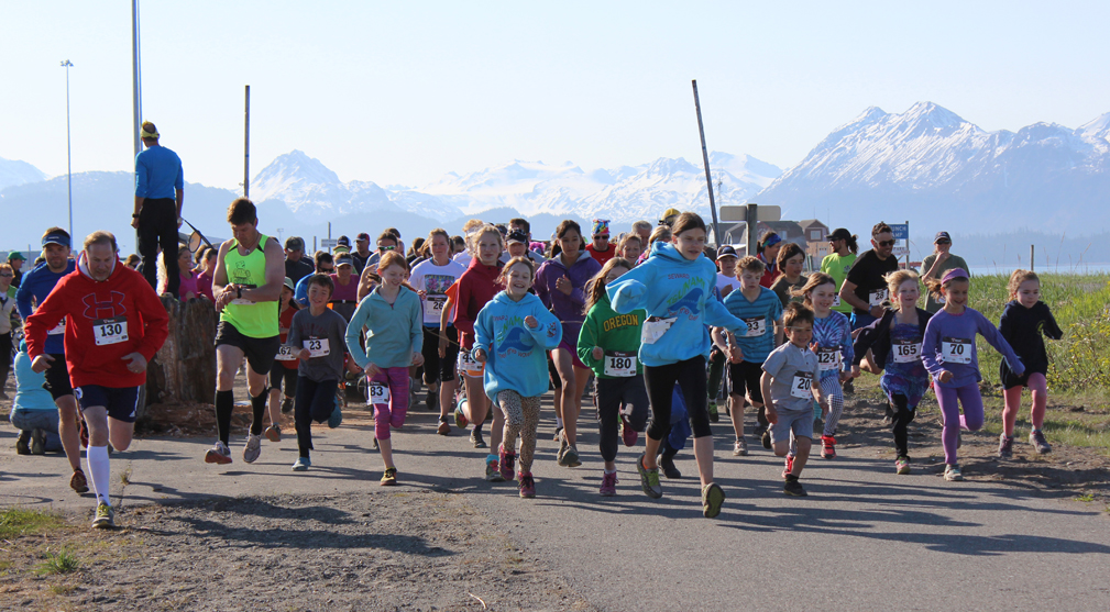 With sunny skies overhead, runners cross the starting line of the annual 5k Migration Run. -McKibben Jackinsky, Homer News