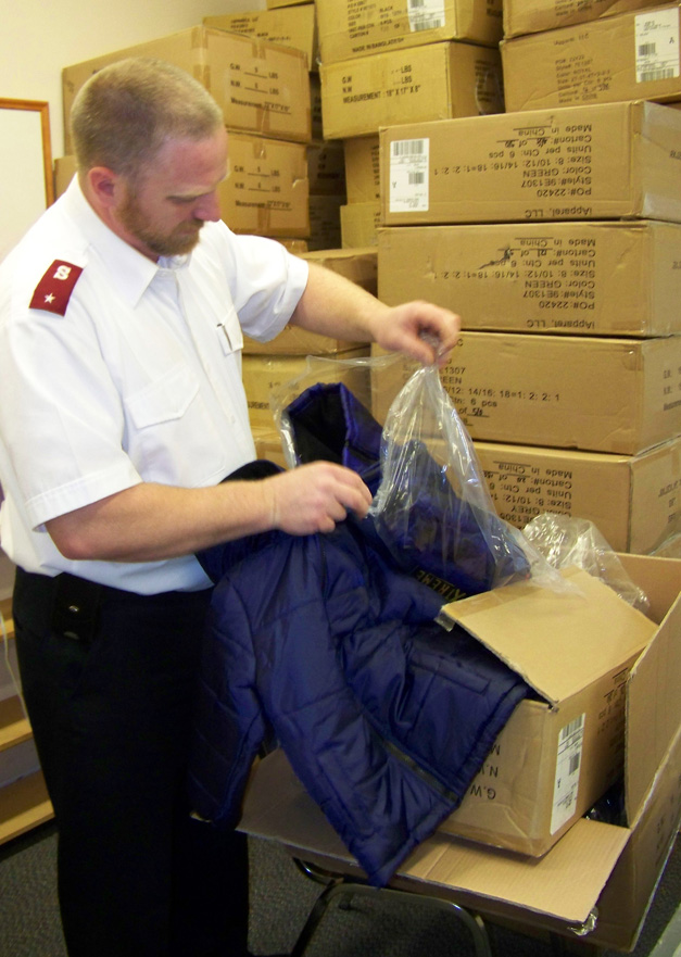 Lt. Jeff Josephson of the Salvation Army in Homer examines one of the 300 new coats donated by Fred Meyer to be given away after the showing of the movie “58:” on Saturday.-Photo by McKibben Jackinsky, Homer News