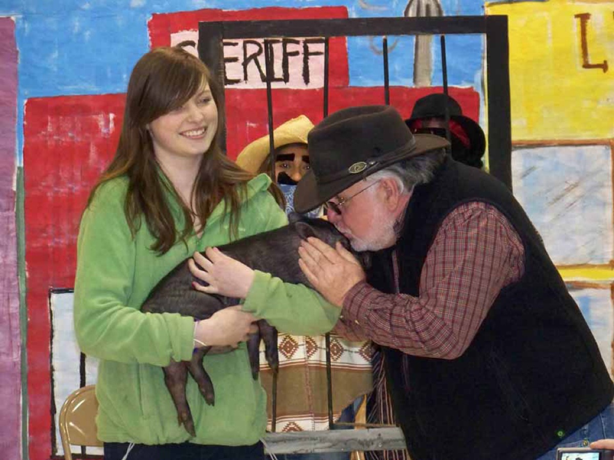 Paul Banks Principal Benny Abraham welcomes Guinevere the pig with a kiss at the end of the school's 2012 readathon. Guinevere, held by Melissa Clark of the 4H Trailblazer Club, was "pignapped" at the beginning of the month-long readathon. Her safe return required the students to read a specific number of minutes.