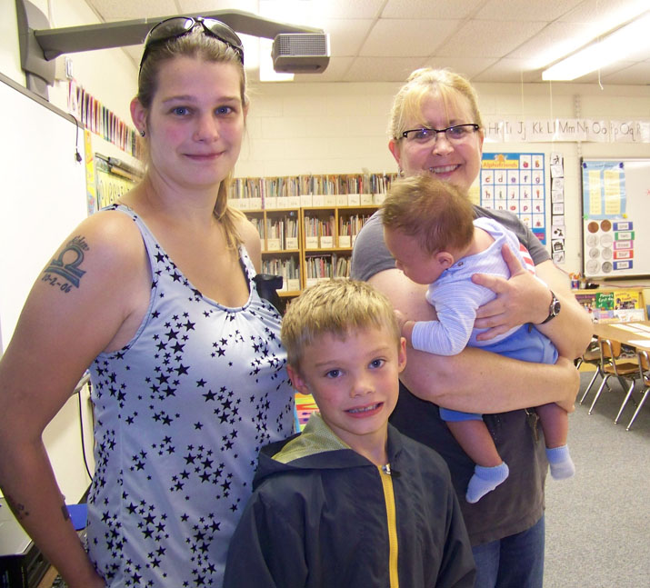 Now in the first grade, Aiden Clark, center, pays a visit to his kindergarten teacher, Jeri McLean, during Paul Banks Elementary School’s meet-your-teacher event on Monday. With Aiden is his mother, Andrea, and 2-month-old brother, Jace, held by McLean.-Photo by McKibben Jackinsky, Homer News