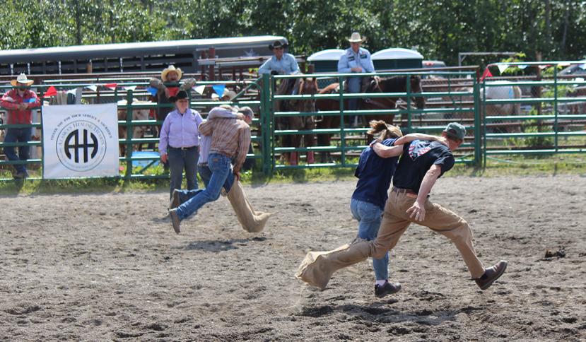 Two teams in the 40-and-older category dash across the Ninilchik Rodeo arena in Saturday’s three-legged race.-Photo by McKibben Jackinsky, Homer News