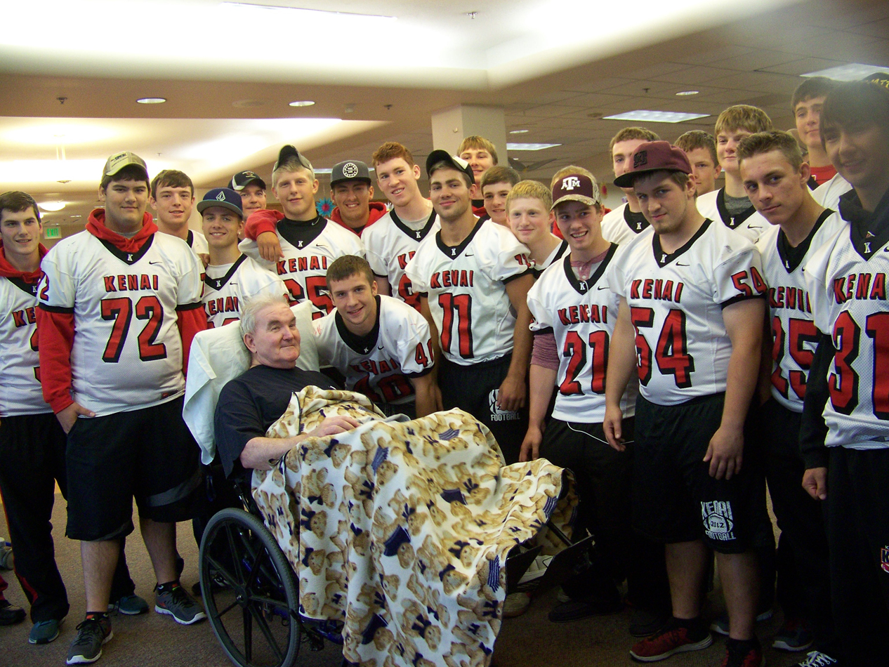 Richard Creary, a resident at South Peninsula Hospital’s Long Term Care unit, poses with his grandson, Kyle Foree, and other members of the Kenai High School football team before their game against Homer on Aug. 31.-Photo by McKibben Jackinsky, Homer News