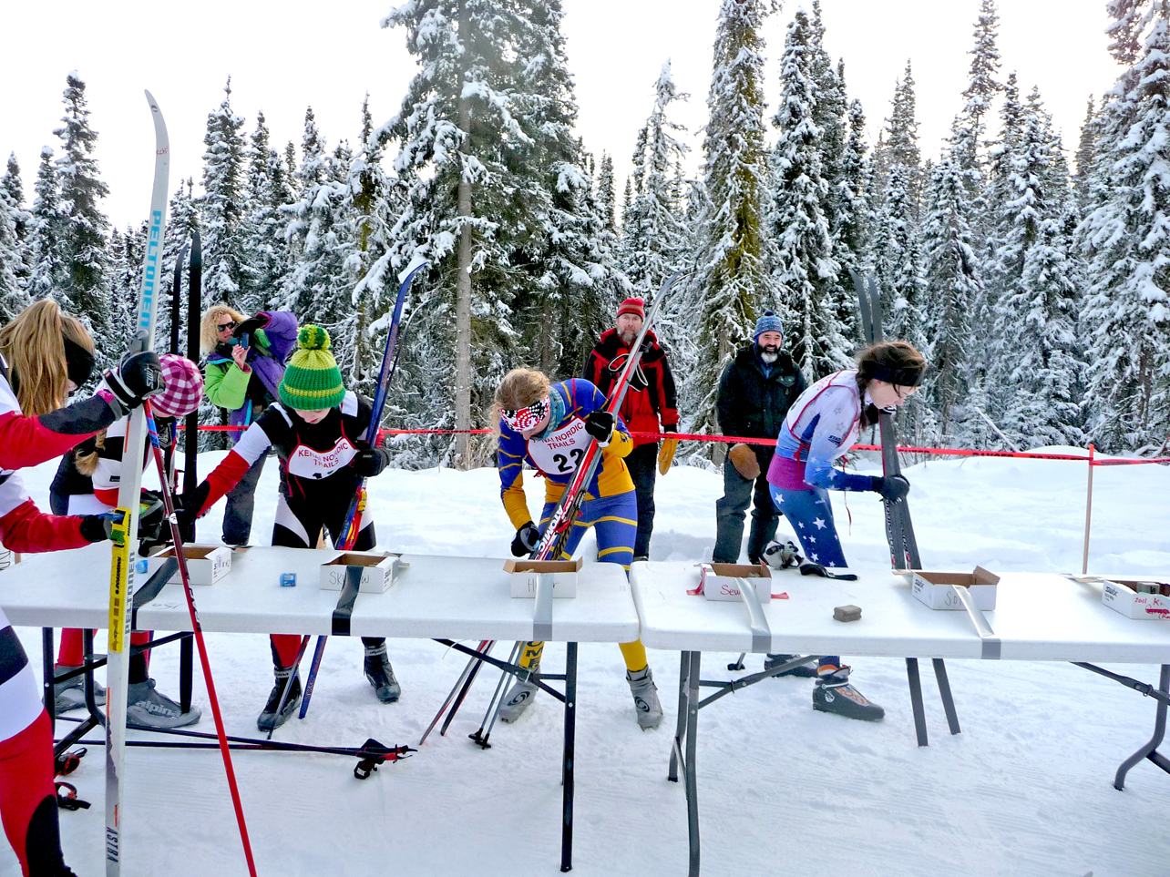 Mariner Tisha Lovett, second from right, applies wax at the kick wax station along with other skiers participating in the Kenai Klassic. One of the things that makes the race unique is that skiers have to apply their own wax.