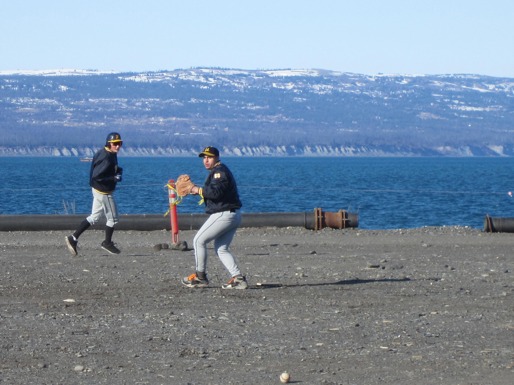 Dick Perez throws the ball during a Mariner practice on the Homer Spit, while Brian Rowe runs. The Mariners’ first game of the season will be May 3 at home.