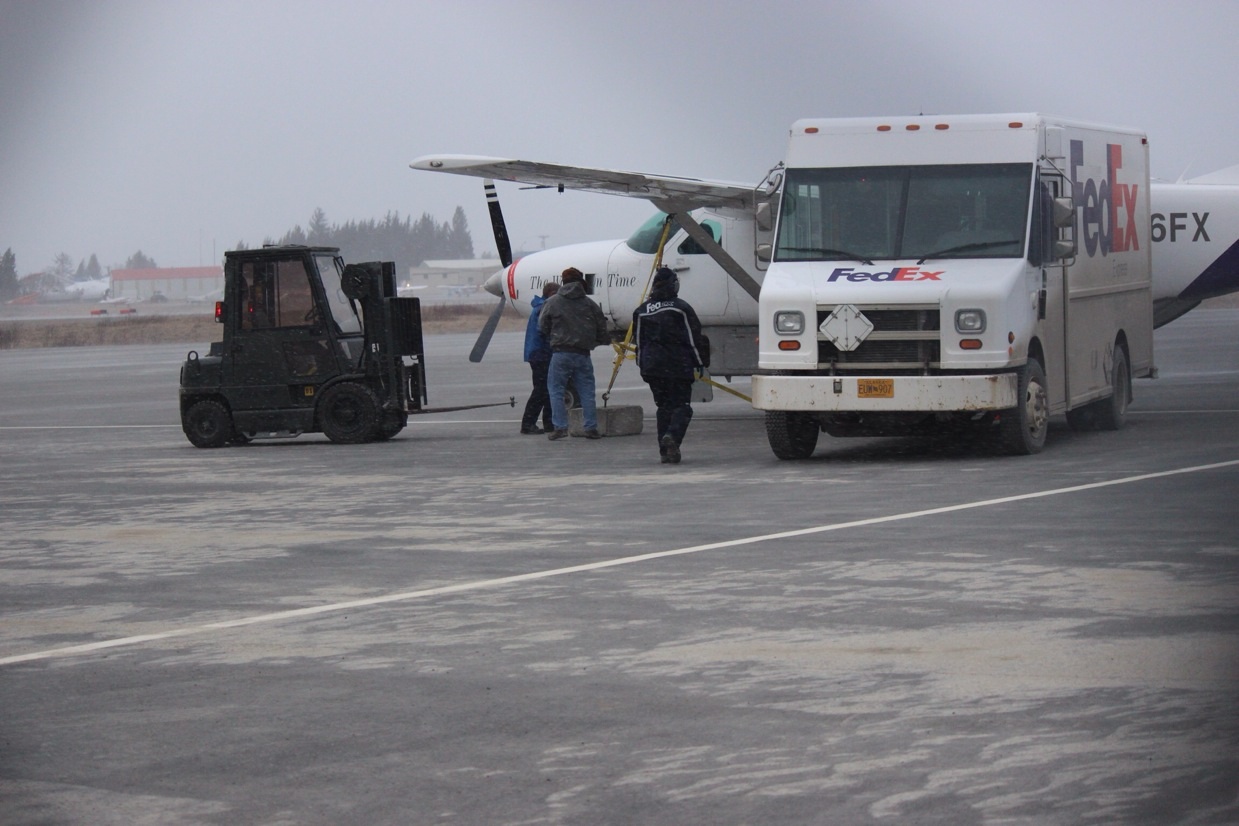 Workers set concrete blocks on the tarmac to tie down a FedEx plan at the Homer Airport.-Photo by McKibben Jackinsky, Homer News