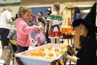Jade Campbell aims to toss marbles in plastic pumpkins during a game as McNeil Canyon parent Tela Bacher watches at the McNeil Canyon Elementary fall festival.-Photo by Anna Frost, Homer News