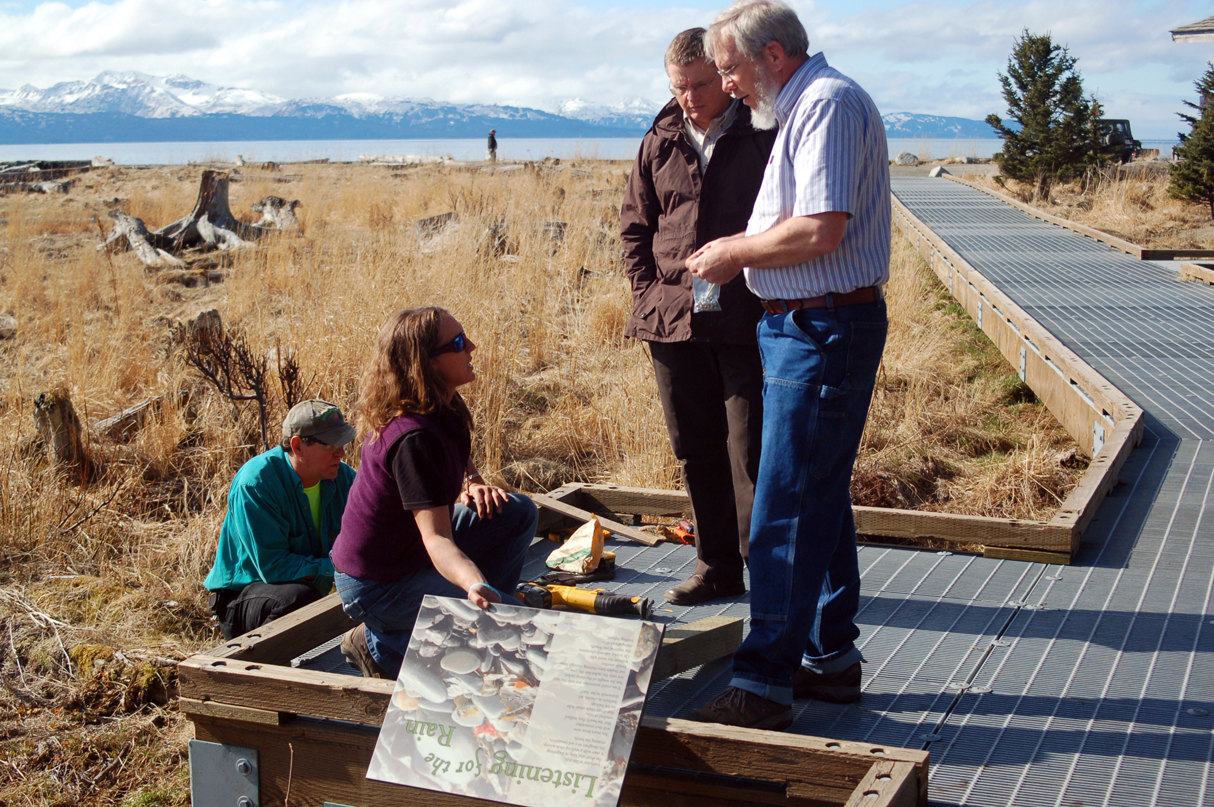 Carey Meyer, public works director, right, and Steve Delehanty, Alaska Maritime National Wildlife Refuge director, second from right, talk with Angie Otteson, parks maintenance director, about installing a Wendy Erd poem on the Beluga Slough Trail. Camp fee collector Bruce Babbitt is at left.-Photo by Michael Armstrong, Homer News