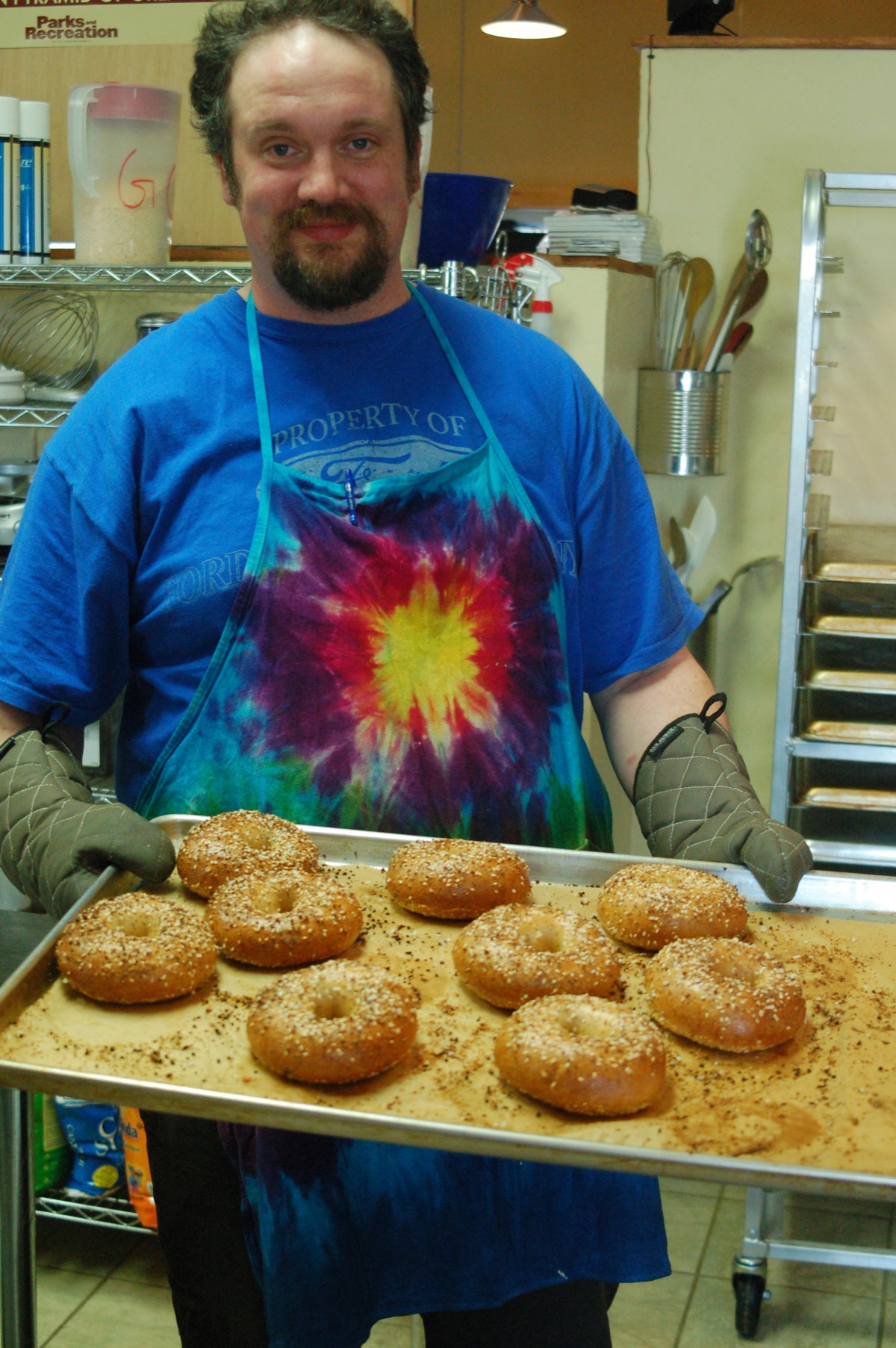 Spice mixtures and sea salt are sprinkled on the coated bagels, the final step before baking.