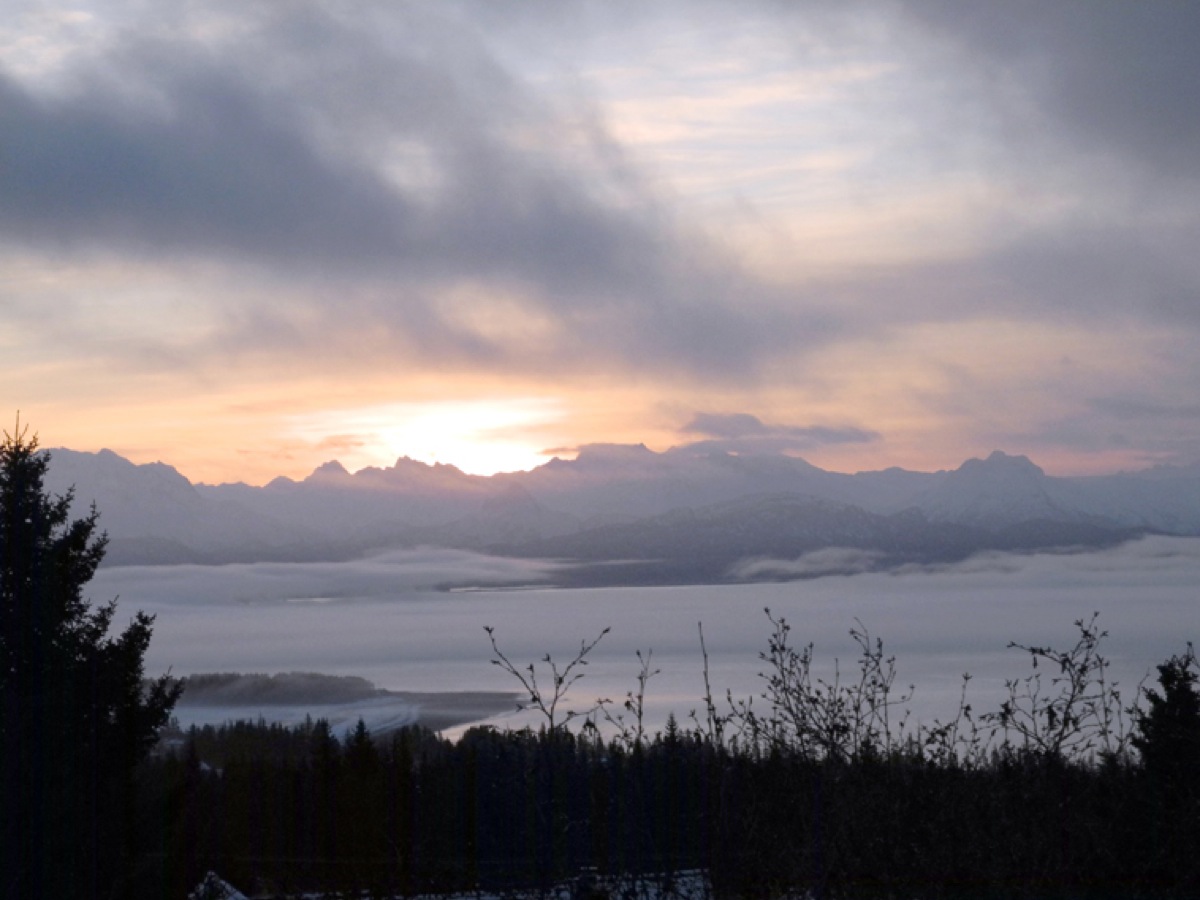 The sun rises over the Kenai Mountains while fog covers Kachemak Bay last Thursday morning, a view many Homer workers see on their drive.