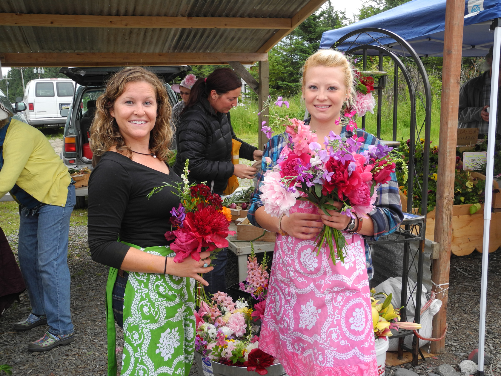 Anna Stewart, left, and Sarah Bodary, right, sell peonies and other flowers at the Homer Farmers Market last August.            -Photo by Michael Armstrong, Homer News