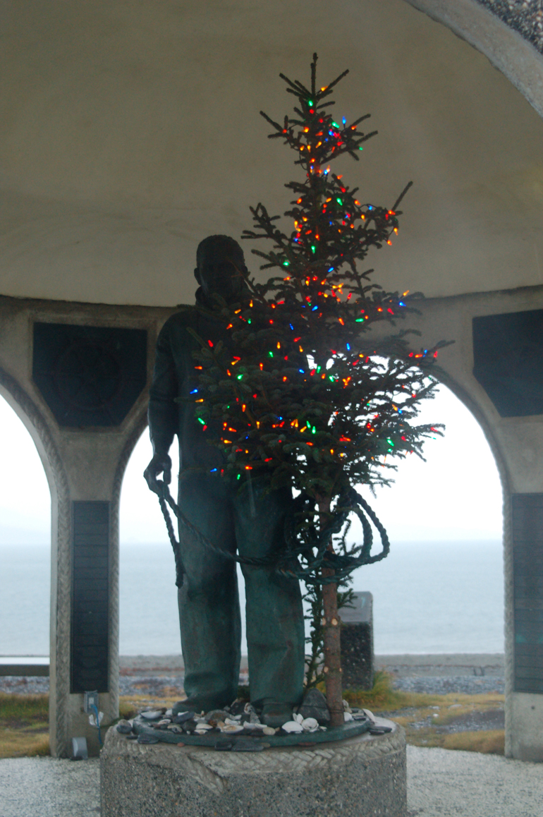 The mariner statue holds a Christmas tree at the Seafarer’s Memorial on the Homer Spit. Part of a Homer Harbor tradition, some mariners also put trees in the masts of fishing boats.-Photo by Michael Armstrong, Homer News