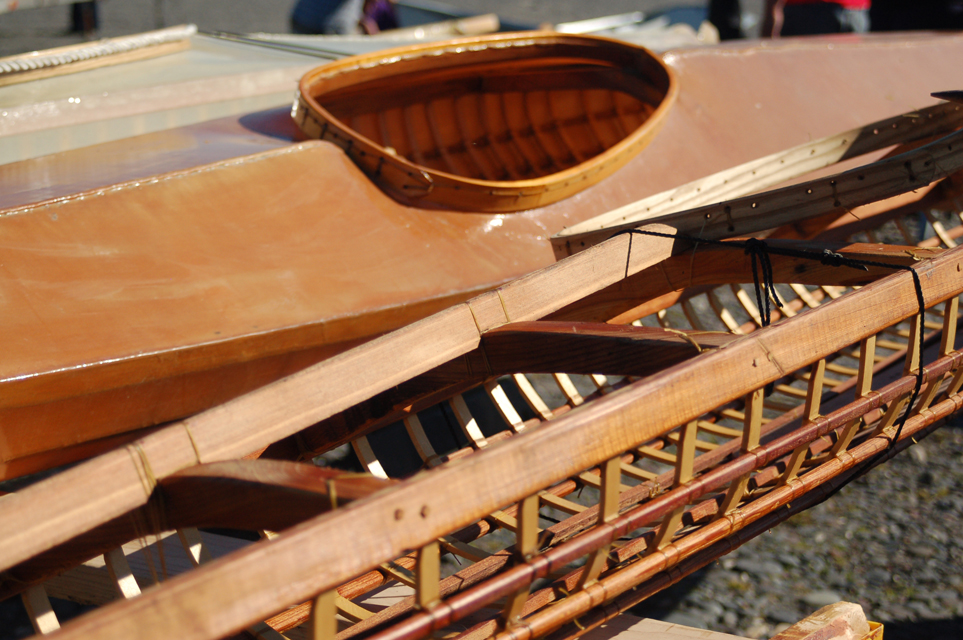 A kayak frame is in front of a kayak with a skin at an earlier wooden boat festival. Below is the festival logo drawn by Chelsea and Marissa Lind.-Photo by Michael Armstrong, Homer News