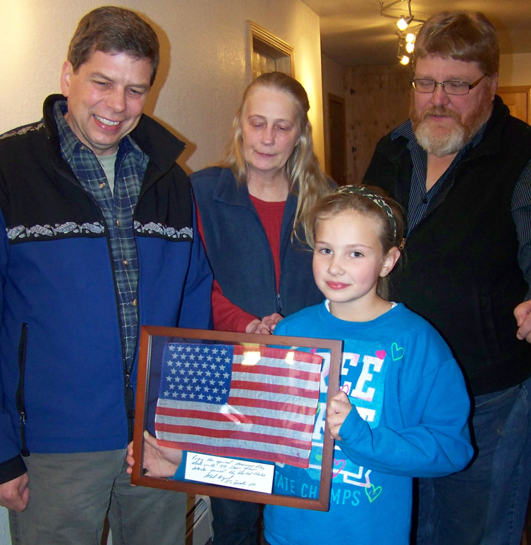 Amber Gilbreath, 8, holds a 49-star parade flag presented on Saturday by Sen. Mark Begich, left, to Nora Anderson, president of the American Legion Auxiliary Post 16, and Tim Clarke, post adjutant.-Photo by McKibben Jackinsky, Homer News