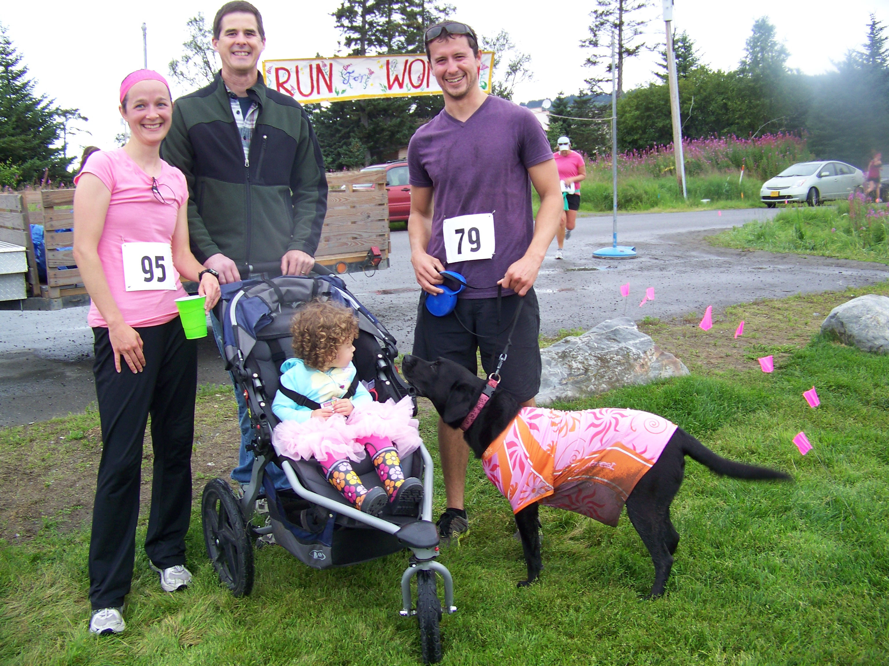 Jeff Williams (center) and Sophia Williams (in stroller) greet runners Brie Drummond, Matt Byrd and Byrd's canine running partner Keala at the end of Sunday's Breast Cancer Run.-Photo by McKibben Jackinsky,  Homer News