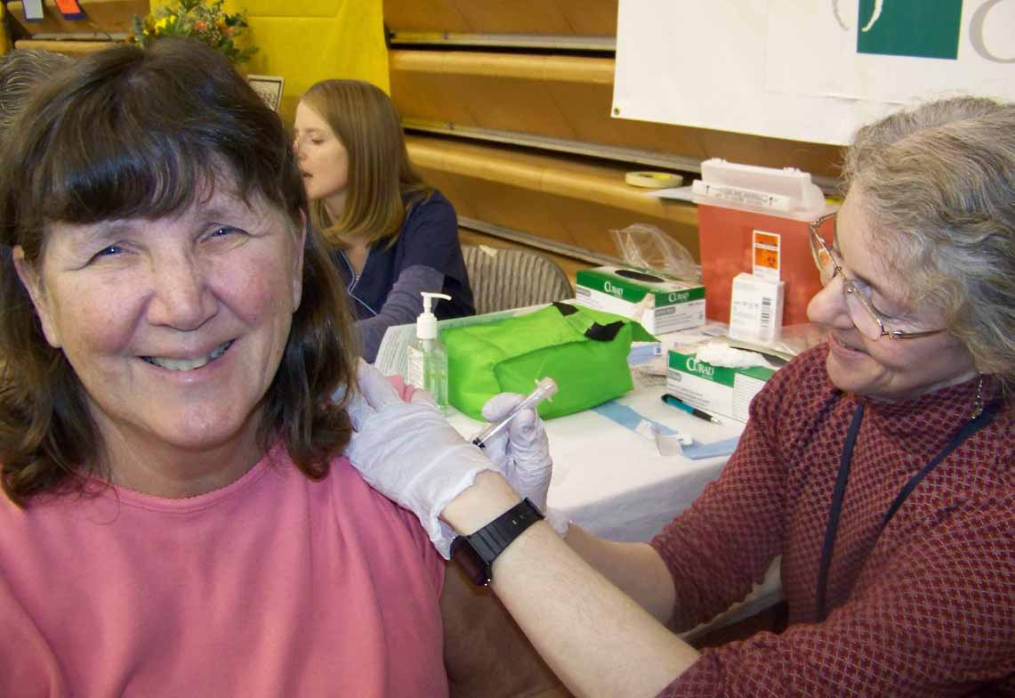 Molly Brann, left,  of Homer receives the 100th flu shot offered by Seldovia Village Tribe at the 2011 Rotary Health Fair. It was administered by Judy Dean, a Public Health nurse. -Photo by McKibben Jackinsky; Homer News