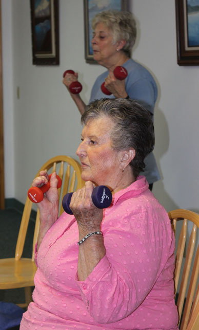 Margaret Lau, standing, and Nancy Smith focus on doing curls with hand weights.-Photo by McKibben Jackinsky, Homer News