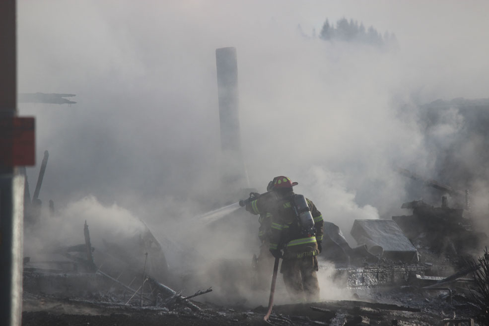 Firefighters from Kachemak Emergency Services, Homer Volunteer Fire Department and Anchor Point Fire and Emergency Medical Services work through the morning to ensure the fire is extinguished.-Photo by McKibben Jackinsky, Homer News