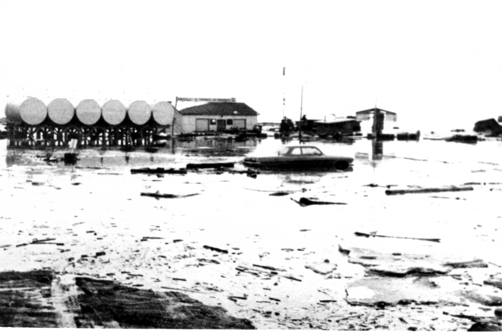 This photo from the Homer News collection donated to the Pratt Museum shows fuel tanks, buildings and a car flooded on the Homer Spit after it subsided about 6 feet during the March 27, 1964, Great Alaska Earthquake.-Photo provided, Pratt Museum, Homer News collection