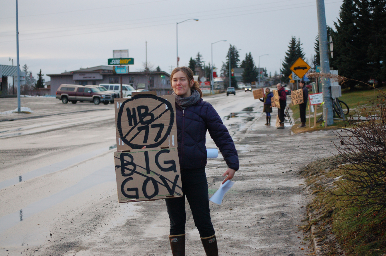 Jessi Dullinger holds a sign protesting House Bill 77 during a demonstration Monday on Pioneer Avenue near the veterans memorial. Dullinger helped organize the small protest.-Photo by Michael Armstrong, Homer News