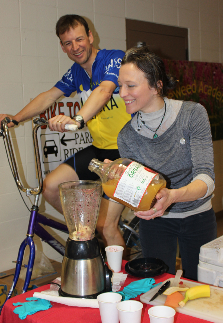 Homer Cycling Club’s Martin Renner provides the energy to operate a blender and Adele Person pours the resulting smoothies for guests at Saturday’s Safe Kids Fair.-Photo by McKibben Jackinsky, Homer News